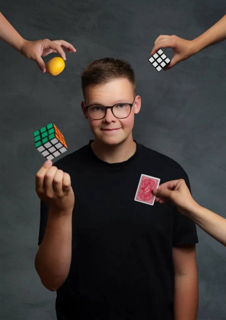 Florian Herz mit Zauberwürfel, umgeben von Händen mit Zitrone, Spielkarte und Würfel